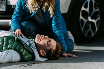 Wall Mural - cropped shot of woman checking heartbeat of victim after traffic collision