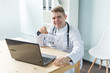 © satura_ - Medicine, working and people concept - doctor sitting at the table with laptop and smiling