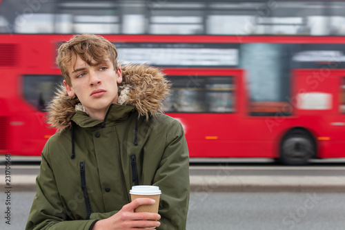 Fotografie, Obraz Male Young Adult Teen Drinking Coffee By Red London Bus