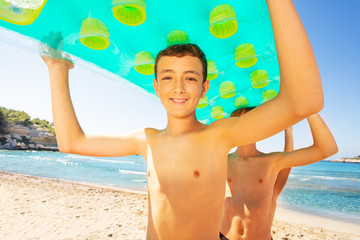 Wall Mural - Cute boy carrying swimming mattress with friends