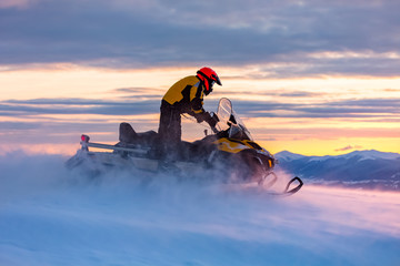 Wall Mural - A man is ridind snowmobile in mountains.