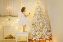 Angel Child Decorating Christmas Tree, Girl Hanging Decoration Presents In Holiday Room With Fireplace