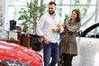© Kalim - Adult couple choosing new car in showroom