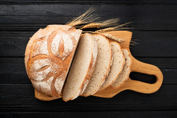 Wall Mural - Freshly baked bread on black wooden table, top view