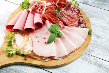 Food tray with delicious salami, pieces of sliced ham, sausage and salad. Meat platter with selection.