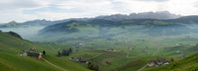 Panorama Landscape View Of The Beautiful Appenzell Region In Switzerland With Ist Rolling Hills And Farms And The Alpstein Mountains Behind