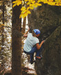 A strong woman rock climber climbing a rock outdoors in forest. Athletes are bouldering outdoors.
