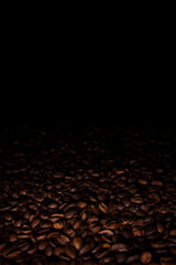 Heap of coffee beans in a dark, with black copy space above