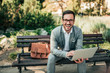 © bnenin - Portrait of a happy businessman using laptop outdoors. Sitting on the bench and looking at camera.