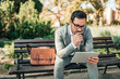 © bnenin - Young businessman working on tablet outdoors.