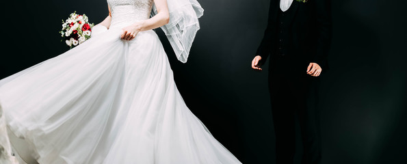  Clothing newlyweds, the bride and groom on a dark background in the studio. Wedding bouquet with roses.