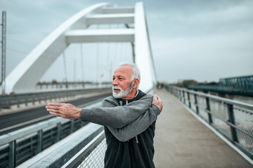 Senior athlete stretching on the bridge in the city.