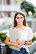 © dianagrytsku - Happy brunette woman holding laptop computer and walking on the street outdoors