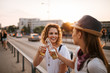 © bnenin - Close-up image of two beautiful young women toasting in the city street.
