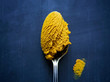 © Carmen Troesser - Turmeric paste in a spoon rests on a blue surface.