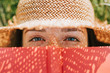 Closeup of woman covering her face with a red book