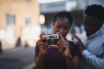 Man teaching his girlfriend how to use a vintage film camera