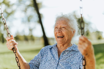 Cheerful senior woman on a swing at a playground