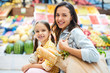 © pressmaster - Cheerful beautiful family doing shopping at farmers market: smiling attractive mom with bag full of fresh product embracing daughter and looking at camera