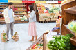 © pressmaster - Outraged young couple in casual clothing standing in healthy food shop and gesturing while   fighting, they confronting with each other, shopping bags in floor