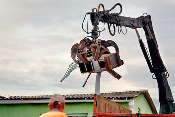 Magnet grapple picking up iron and steel metal garbage for transferring and recycling. Truck with metal grab is loading industrial and household waste on scrap yard. Demolition and sorting concept