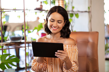 technology and people concept - happy woman with tablet pc computer at cafe or coffee shop