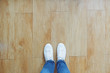 © Nuchylee - Selfie of feet in fashion sneakers on wooden floor background, top view with copy space