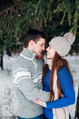 Wall Mural - Young couple hugging and kissing in the forest in winter.