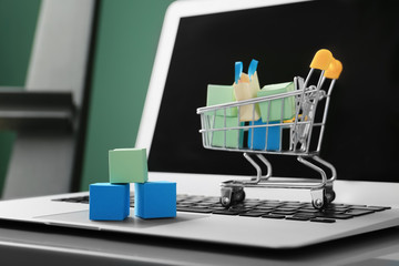 Small cart and laptop on table. Internet shopping concept