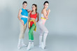 © LIGHTFIELD STUDIOS - full length view of attractive young sportswomen posing together and smiling at camera on grey