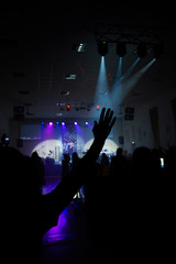 raised hands in a dark concert hall against the background of the stage