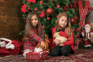 Two Girls Under Christmas Tree are Playing with Toys