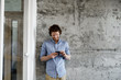 © LUMINA IMAGES - Young casual Caucasian  businessman standing at work and typing on his cell phone.