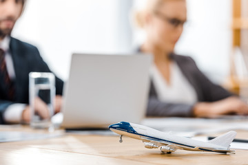 toy airplane at wooden table with office worker on blurred background