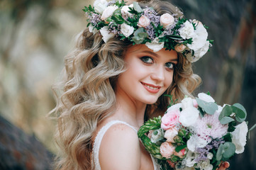 Wall Mural - beautiful bride in nature in a coniferous forest in a wreath on her head and a luxurious wedding dress