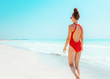 © Alliance - modern woman in red swimsuit on seacoast walking