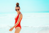 Fototapeta  - happy young woman in red swimwear on seashore having fun time