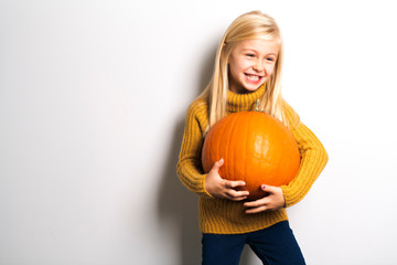 Wall Mural - A Cute girl 5 year old posing in studio with pumpkin