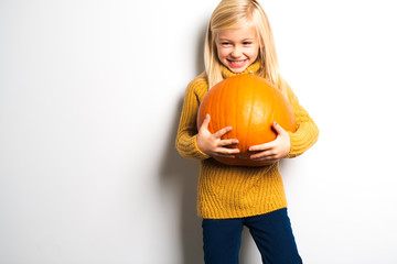 Wall Mural - A Cute girl 5 year old posing in studio with pumpkin