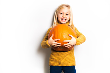 Wall Mural - A Cute girl 5 year old posing in studio with pumpkin