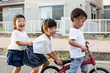 © Mint Images - Smiling friends playing on street with bicycle