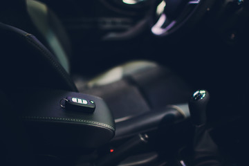 Wall Mural - Closeup inside vehicle of wireless key ignition. Start engine key. Car key remote in black perforated leather interior. Car detailing. Keys close up.