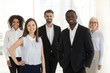 © fizkes - Portrait of happy diverse work team standing looking at camera motivated for success and new achievements, smiling multiethnic managers or workers feel excited posing in office together