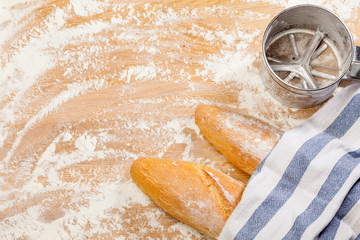 Artisanal French baguettes and flour sieve or sifter on a table