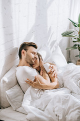 Wall Mural - beautiful young couple embracing in bed in morning