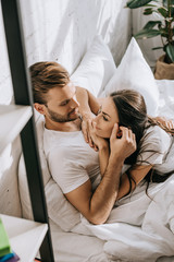 Wall Mural - high angle view of happy young couple relaxing and chatting in bed in morning