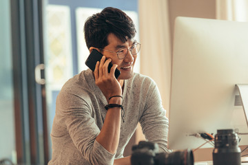 Wall Mural - Photo editor talking on phone at his workdesk