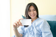 © Success Media - Smiling female patient on bed showing blank credit card.