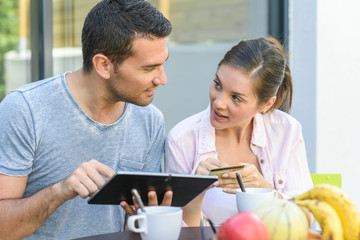 Couple talking and buying something online with a tablet outdoors