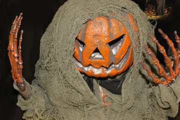 Pumpkin head zombie monster Halloween decoration on black background - selective focus